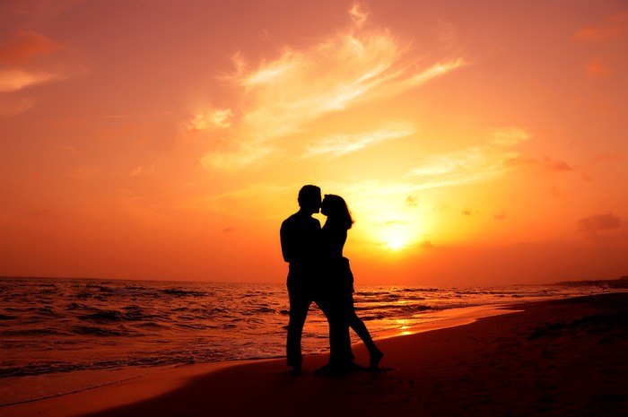 an amorous couple are kissing at sundown